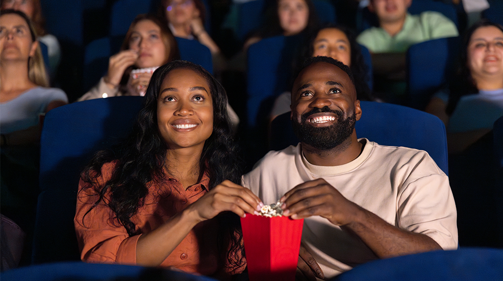 Loving couple watching a movie at the theatre and eating popcorn